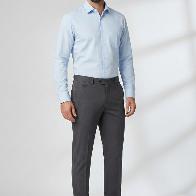 Man wearing a light blue dress shirt and gray pants against a white background