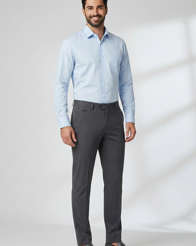 Man wearing a light blue dress shirt and gray pants against a white background