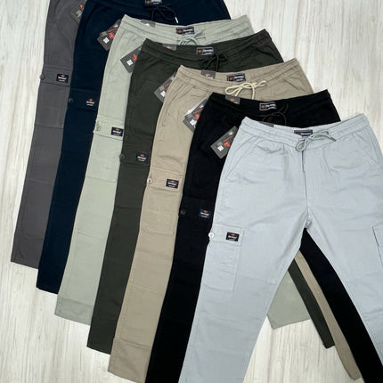 Set of multiple pairs of pants in various colors on a light wooden floor.